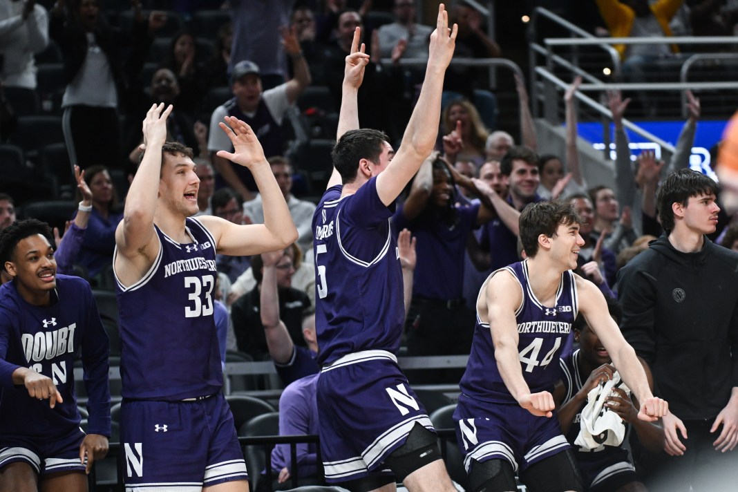 Northwestern Wildcats forward Luke Hunger (33), center Keenan Fitzmorris (5), and guard Angelo Ciaravino (44) celebrate from the bench after a play during the second half against the Minnesota Golden Gophers at Gainbridge Fieldhouse on March 12, 2025.