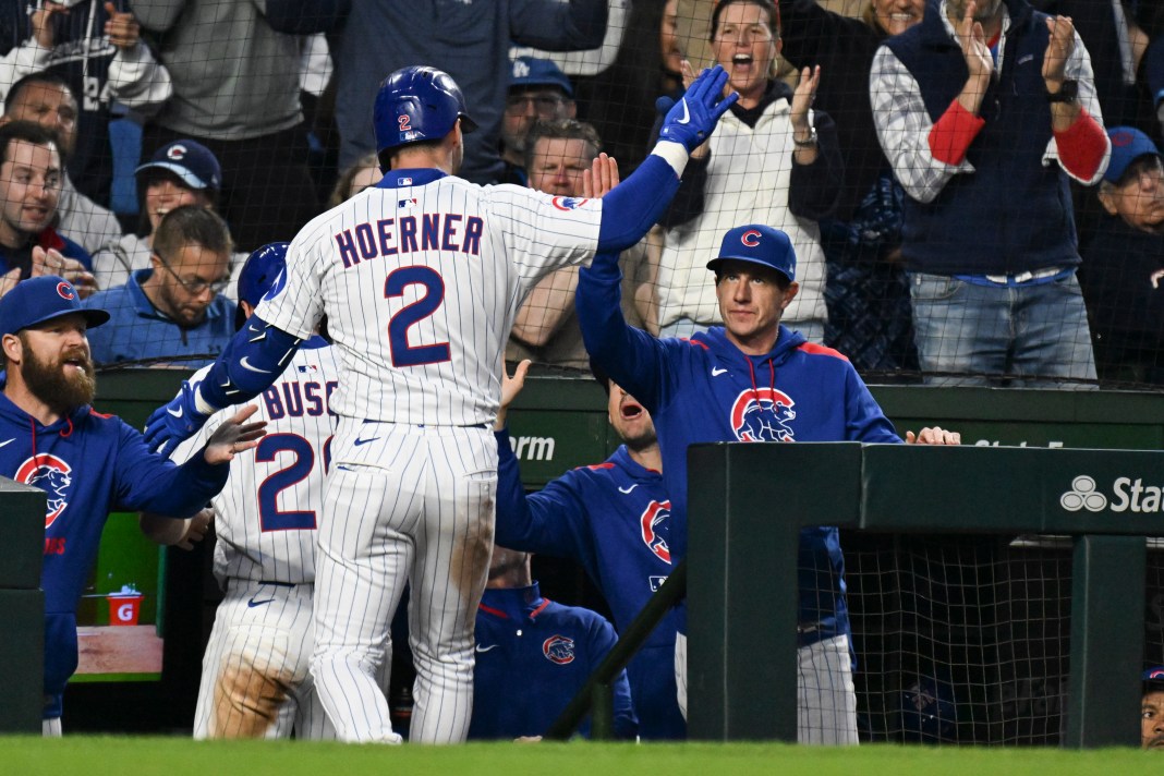 Chicago Cubs second baseman Nico Hoerner (2) high fives manager Craig Counsell (11) after hitting an RBI sacrifice fly against the Los Angeles Dodgers during the fifth inning at Wrigley Field in Chicago, Illinois, on April 23, 2025.