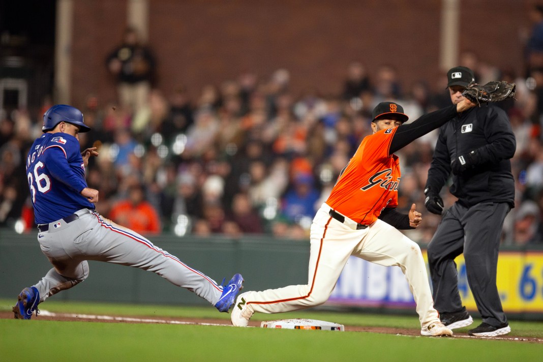 Texas Rangers left fielder Wyatt Langford (36) gets back to first base ahead of a pickoff throw to San Francisco Giants first baseman LaMonte Wade Jr. (31) during the eighth inning at Oracle Park in San Francisco, California, on April 25, 2025. Umpire Todd Tichenor watches the play.