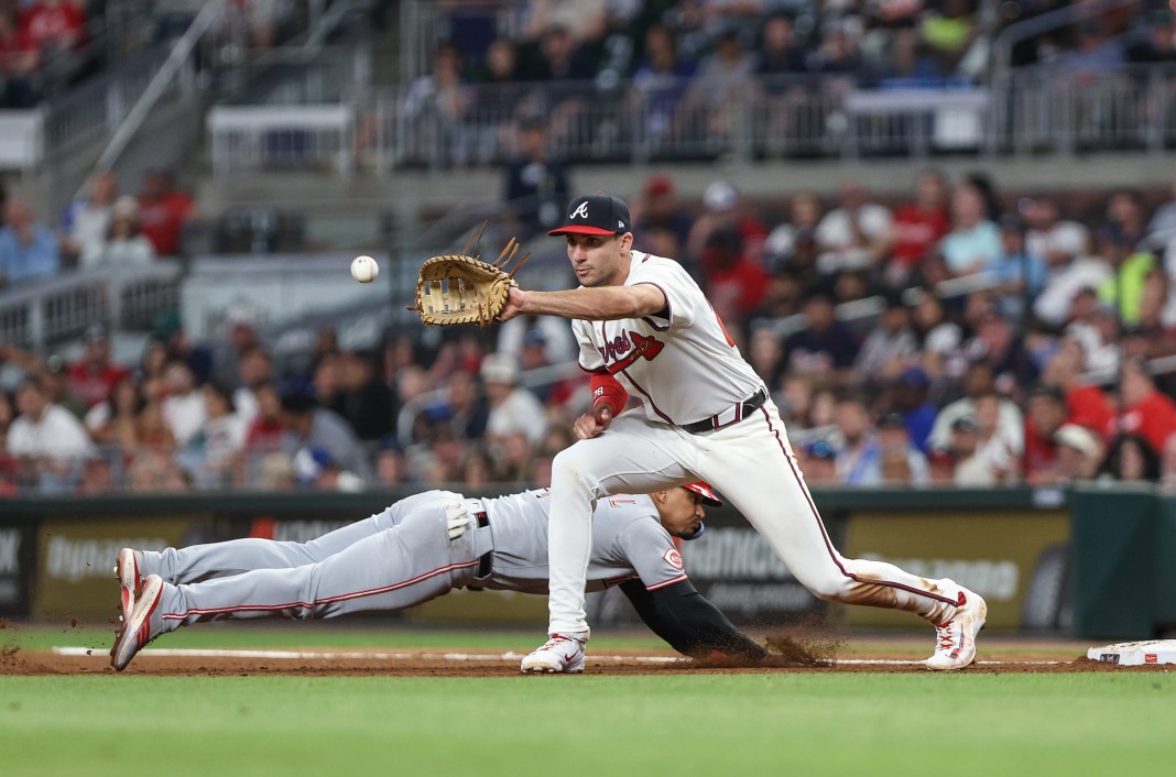 Cincinnati Reds second baseman Santiago Espinal (4) dives back to first base against Atlanta Braves first baseman Matt Olson (28) during the eighth inning at Truist Park in Cumberland, Georgia, on May 6, 2025.